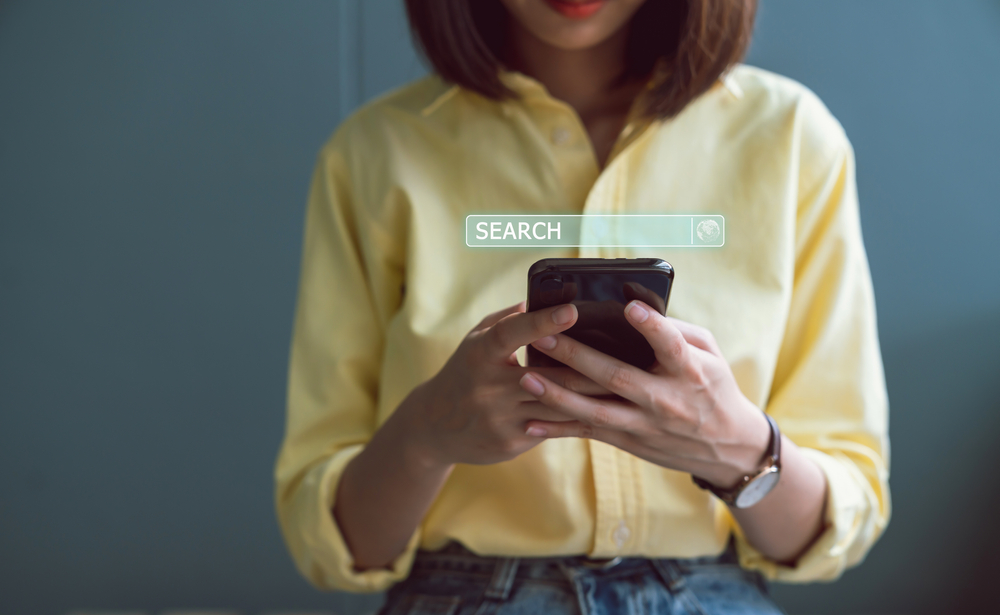 Woman holding a phone with a visible search bar